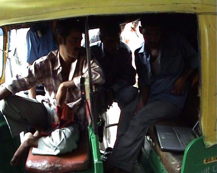 Drivers huddled around and inside an auto richshaw, watching the films and talking.